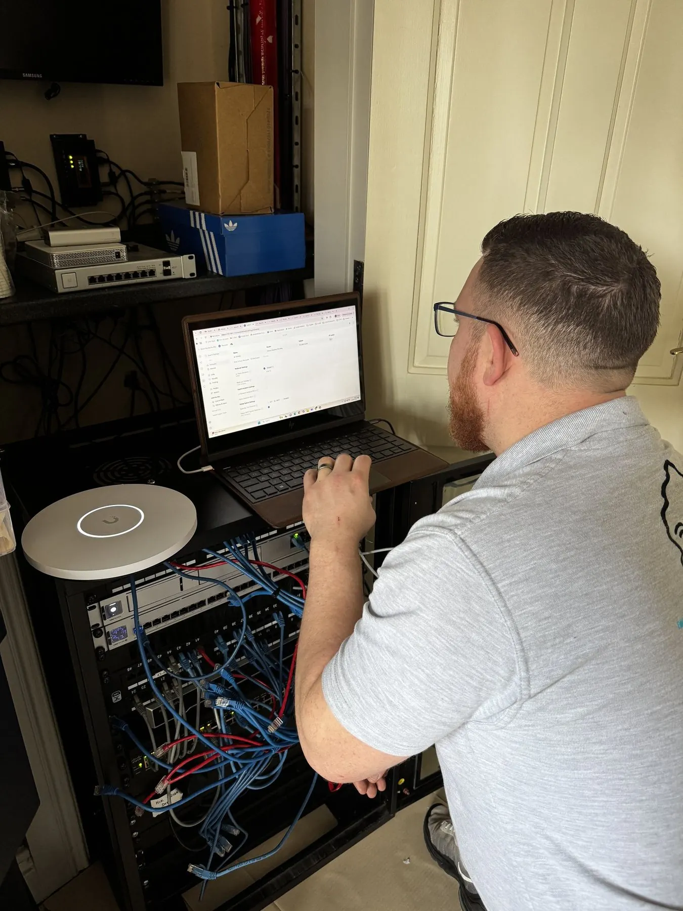 True Tech engineer configuring a commercial network cabinet for business Wi-Fi and CCTV systems