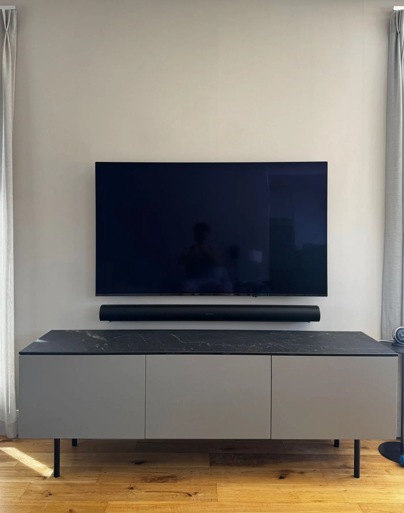Residential wall mounted TV and soundbar installation above a media unit.