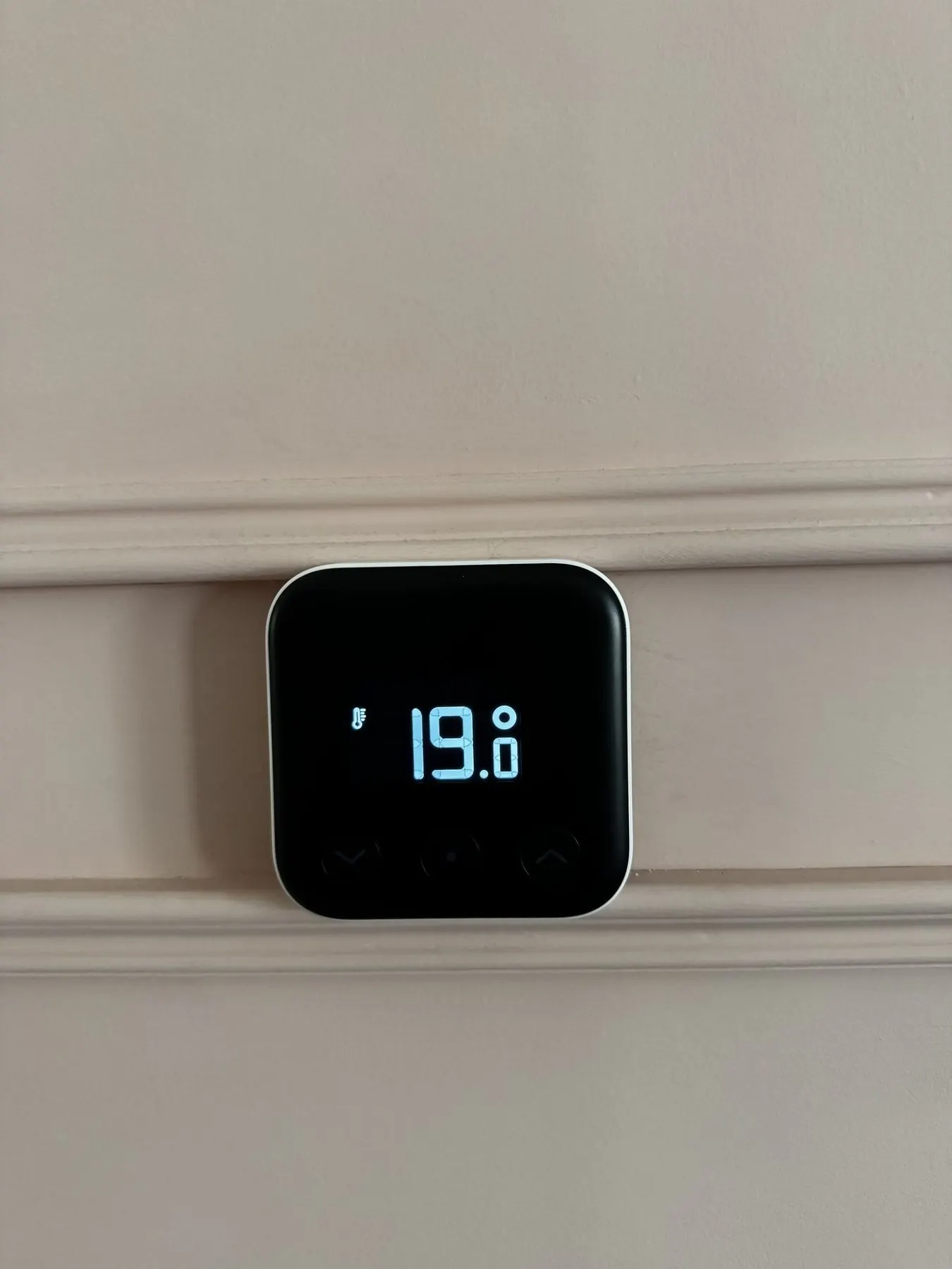 Tado smart thermostat installed in a living room.